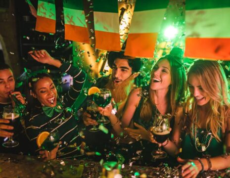 Happy multi-ethnic friends drinking and having fun at Saint Patrick's day night club party