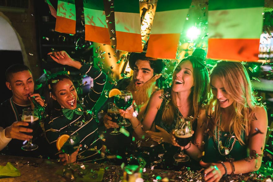 Happy multi-ethnic friends drinking and having fun at Saint Patrick's day night club party