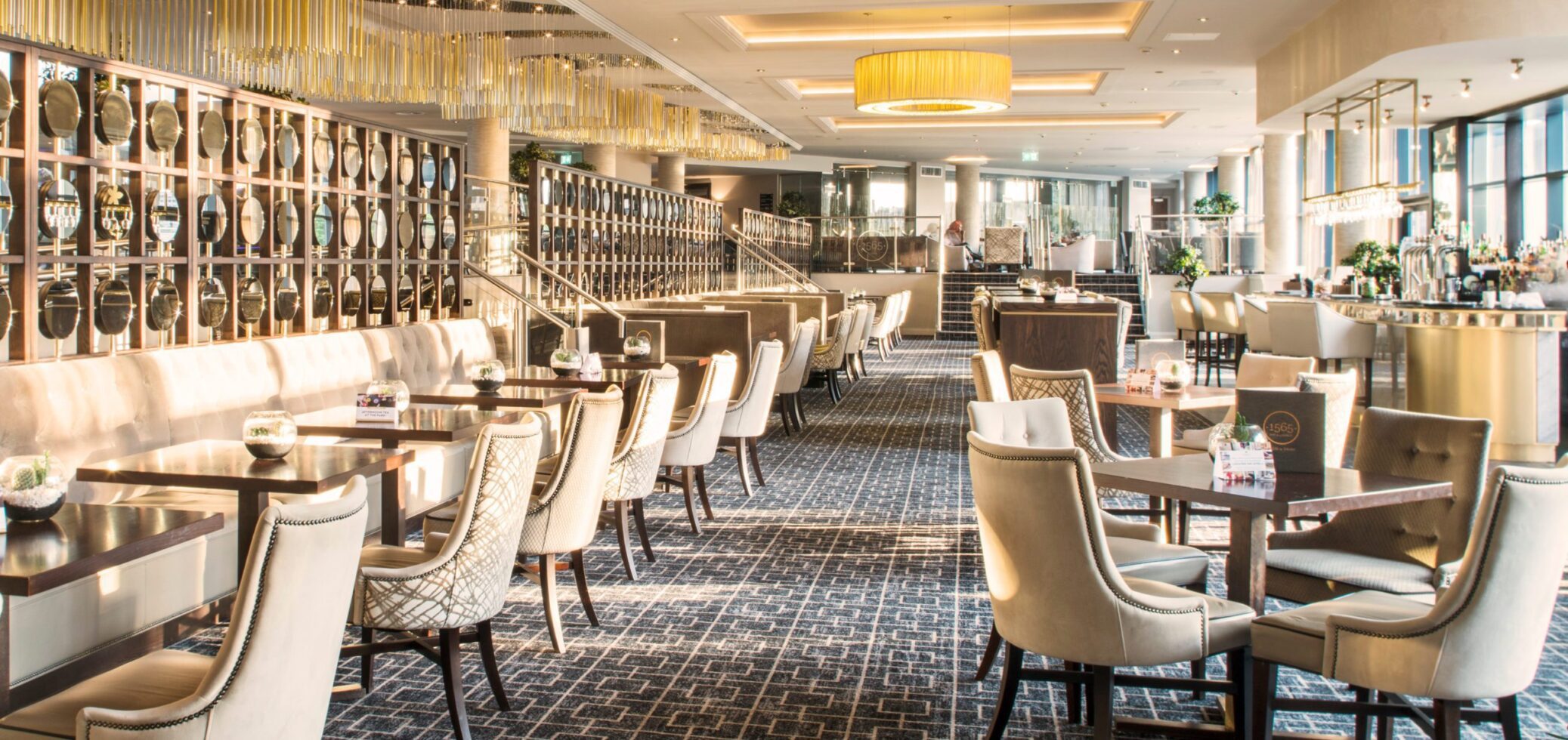 Large bar space with rows of tables, golden decorations and sunlight pouring in