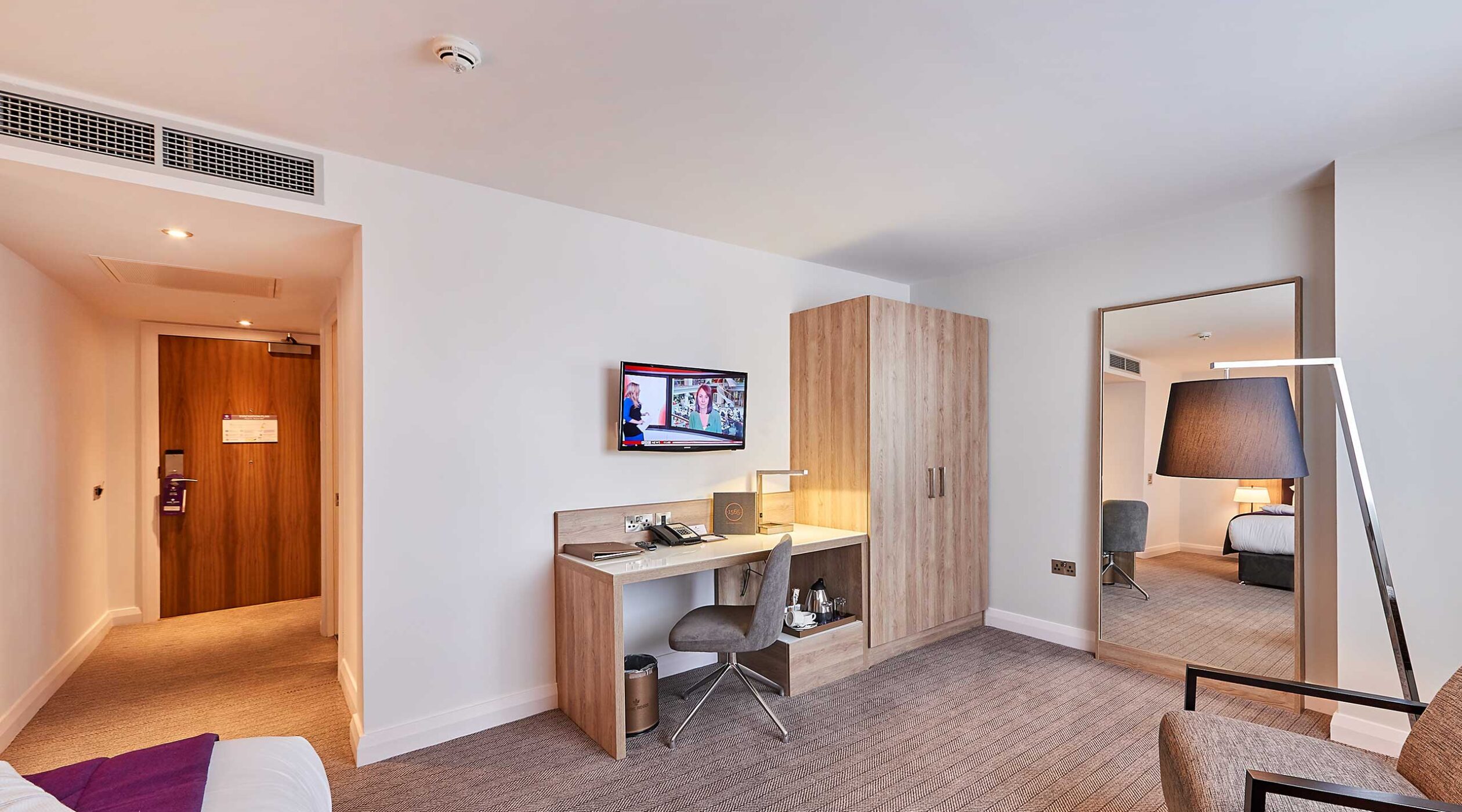 Park Regis Birmingham deluxe accessible room with large floor space, a desk, television, wardrobe, double bed and floor length mirror
