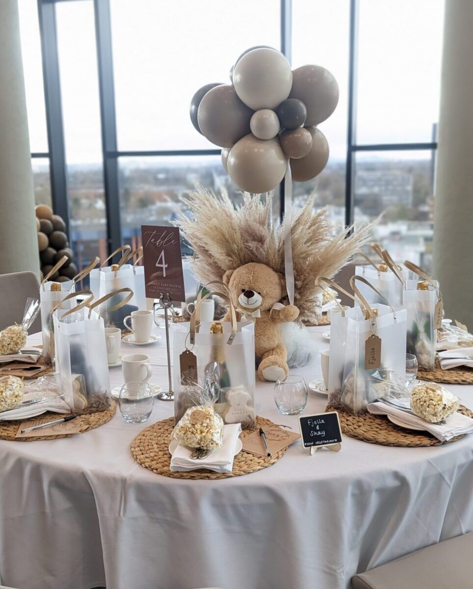 Baby shower with a table decorated with balloons and a teddy