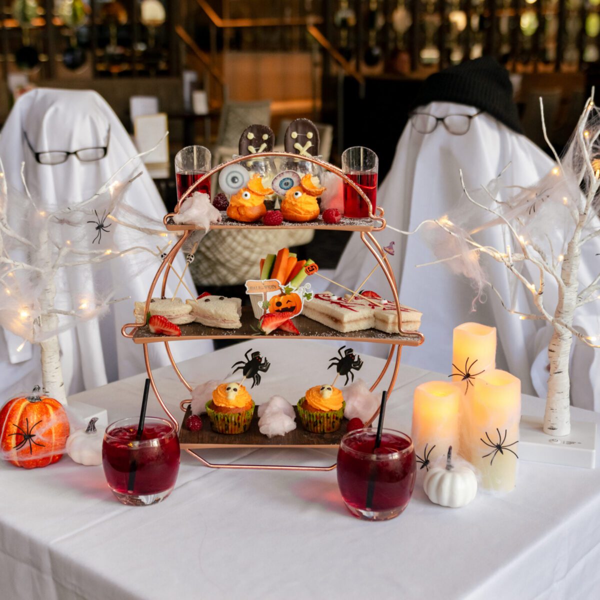 Two people dressed up as ghosts sitting with Park Regis Birmingham's Halloween version of their Children's Afternoon Tea